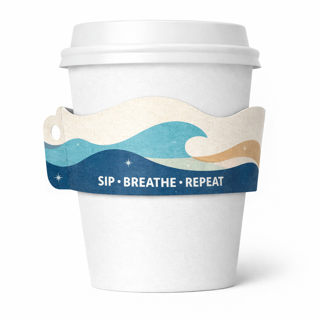 White paper cup with a wavy, ocean-themed sleeve in blues and beige reading “SIP • BREATHE • REPEAT.