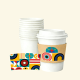 Stack of blank white paper cups with a lidded cup wrapped in a kraft sleeve featuring colorful geometric shapes; a matching flat sleeve sample is shown in front.