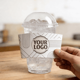 Hand holding a white geometric-line cup sleeve with a customizable logo against a clear iced drink cup with a dome lid.